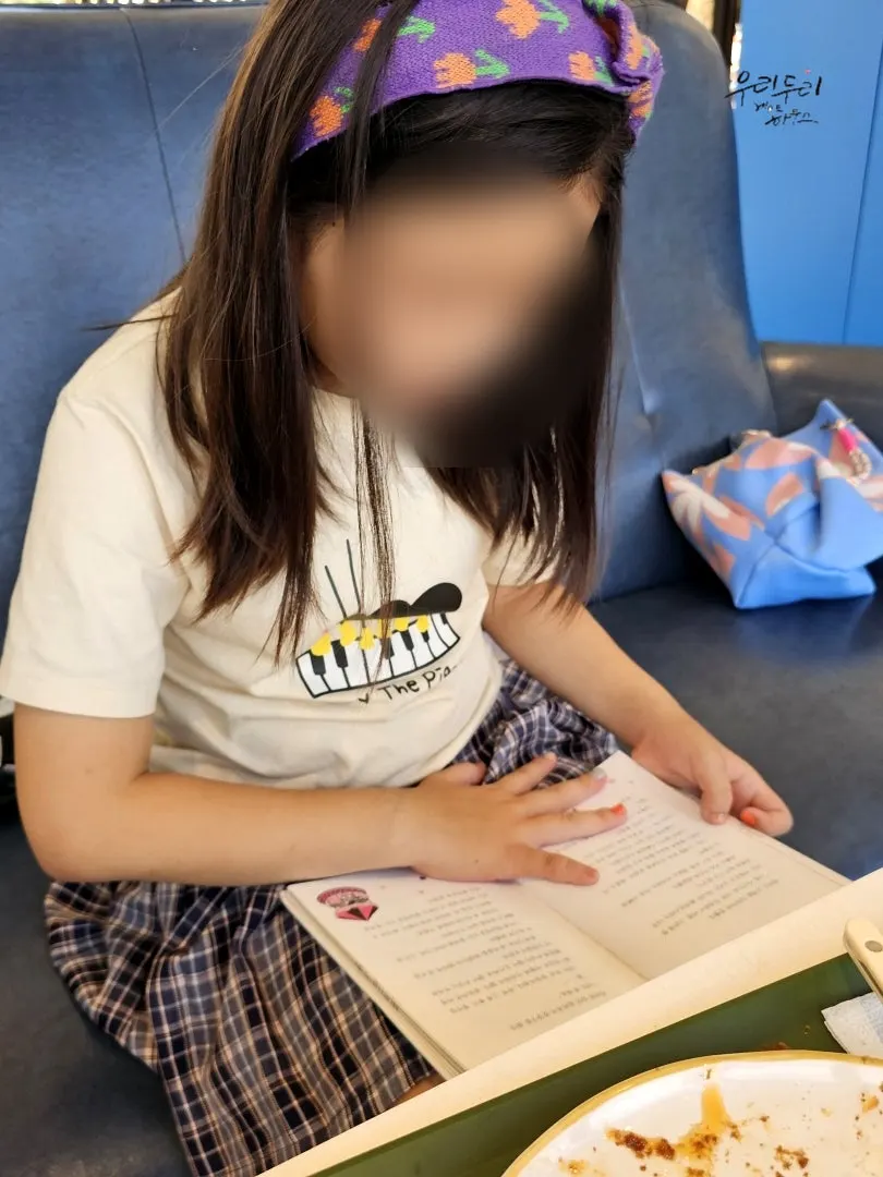 A child reading a book while eating a snack at the café