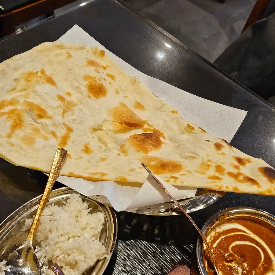 Naan dipped into butter chicken curry