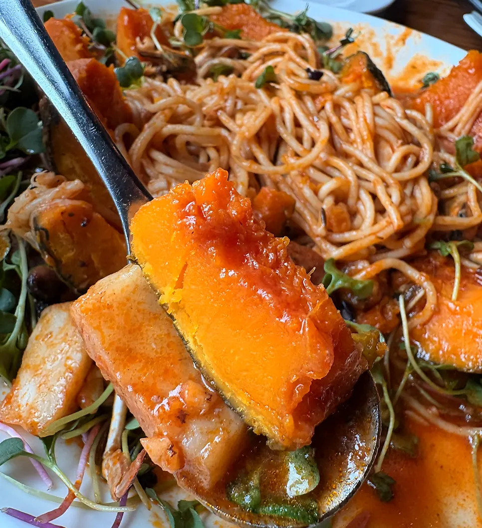 Pumpkin cut open with seafood placed on top of the pasta