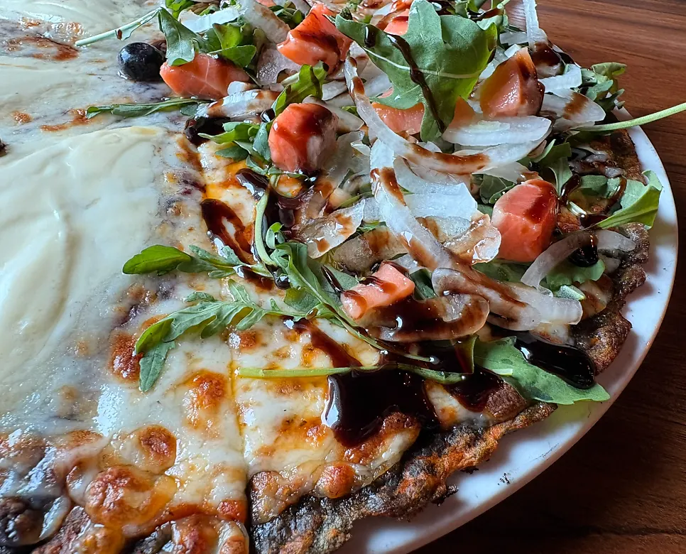 A slice of arugula smoked salmon pizza