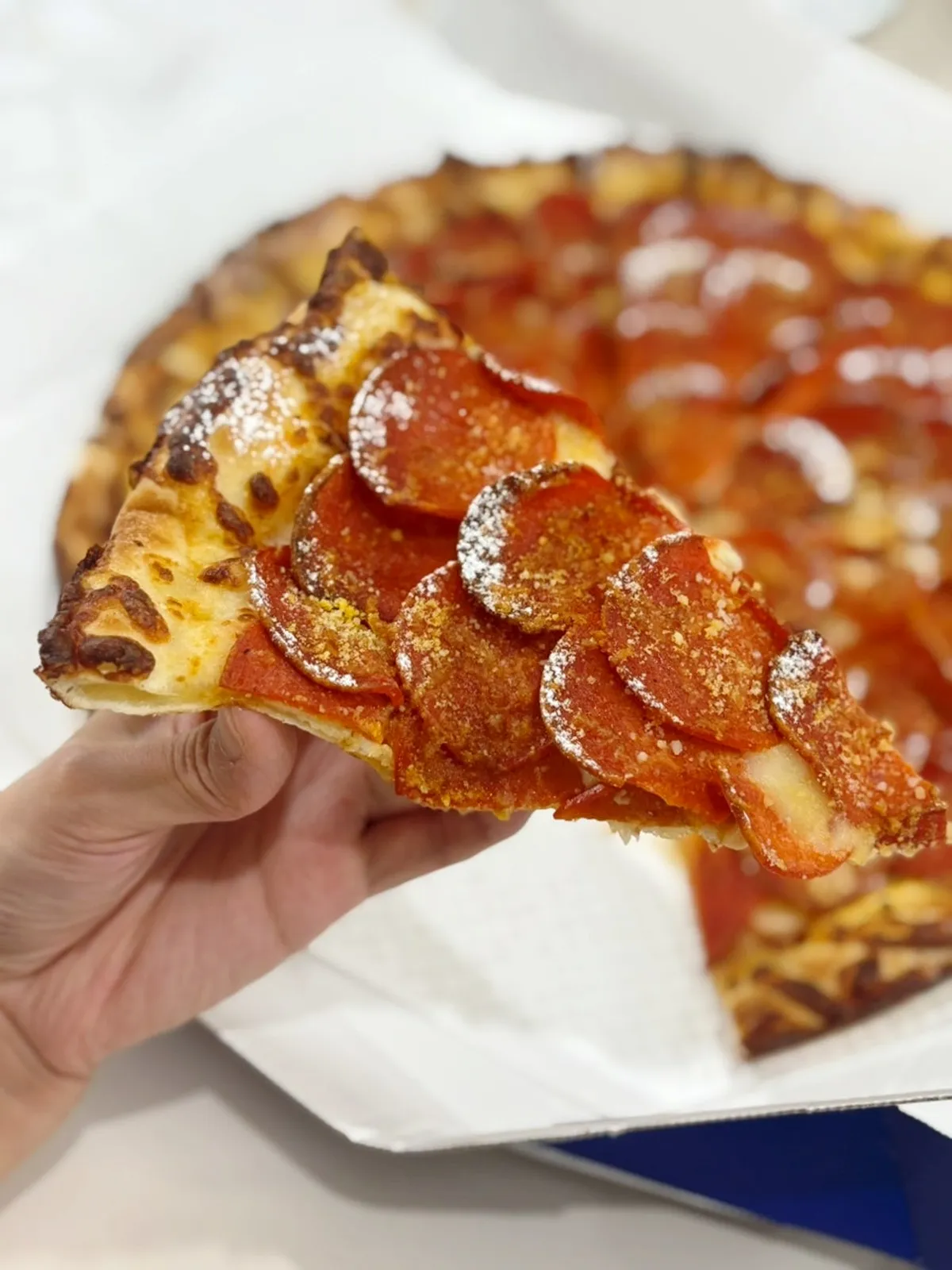 Slice of double pepperoni pizza lifted up