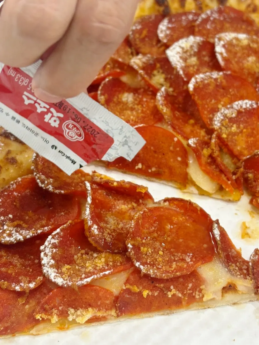 Pepperoni pizza eaten with hot sauce