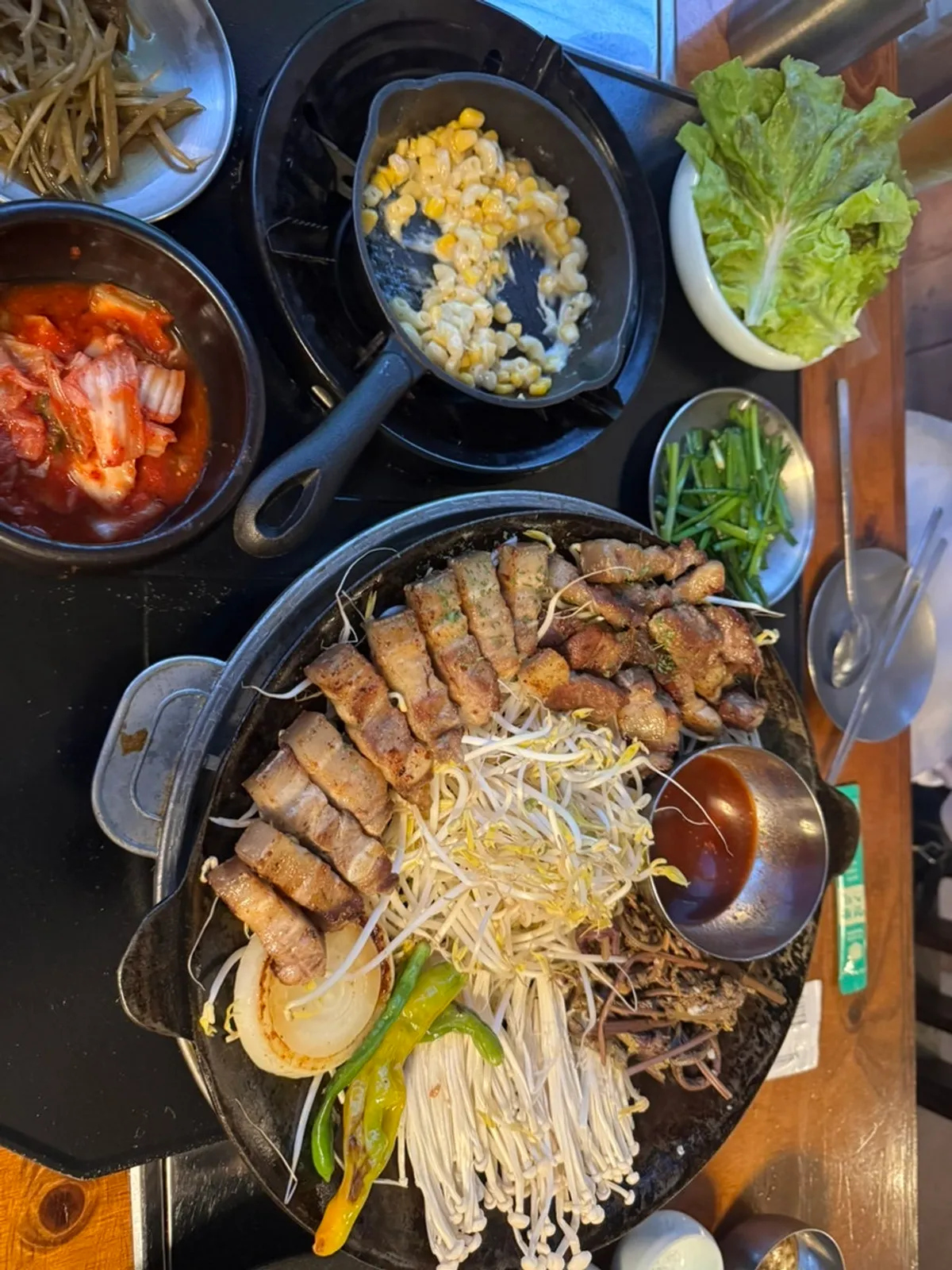 Spicy woo-samgyeop doenjang jjigae served alongside a piece of grilled meat