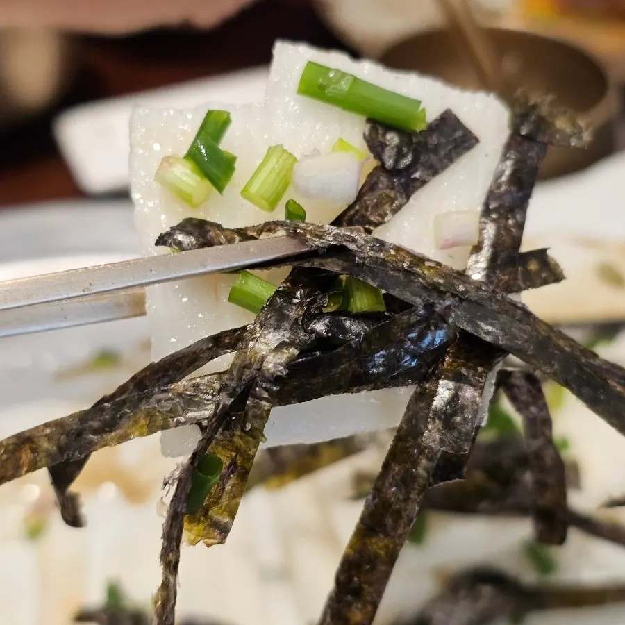 Chopsticks dipping yam salad into the sauce
