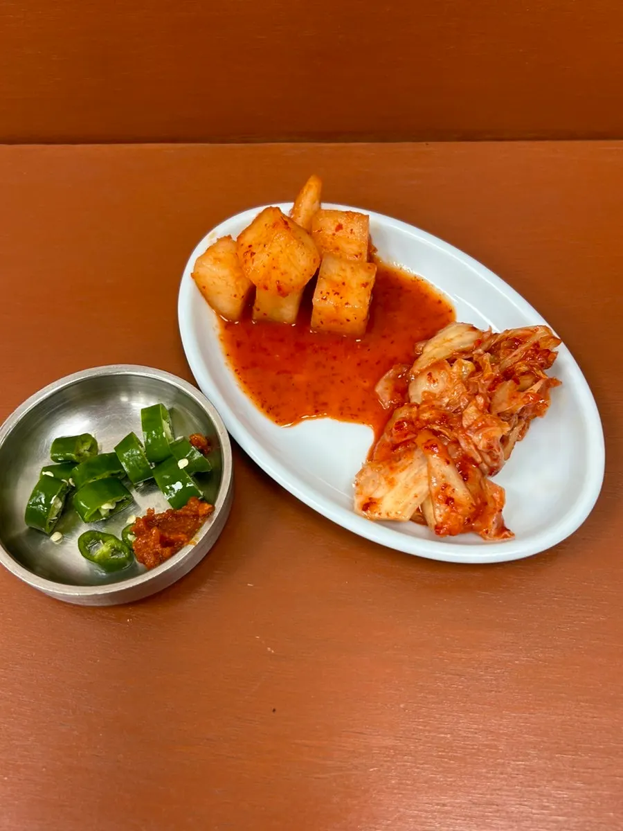 Side dish containers at the self-serve bar filled with garlic chives and vegetables