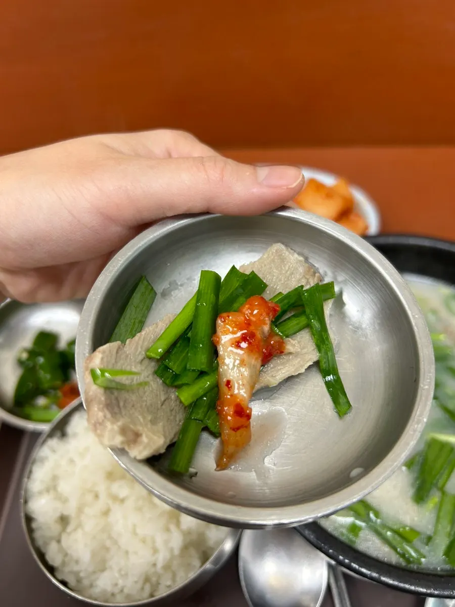 A spoon piled high with meat from the pork soup