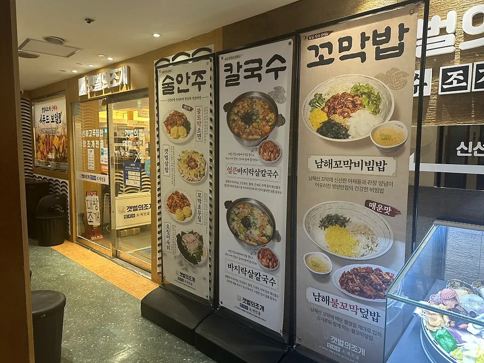 Menu photos for kalguksu, cockle bibimbap, and clam hot pot posted at the 2nd-floor entrance