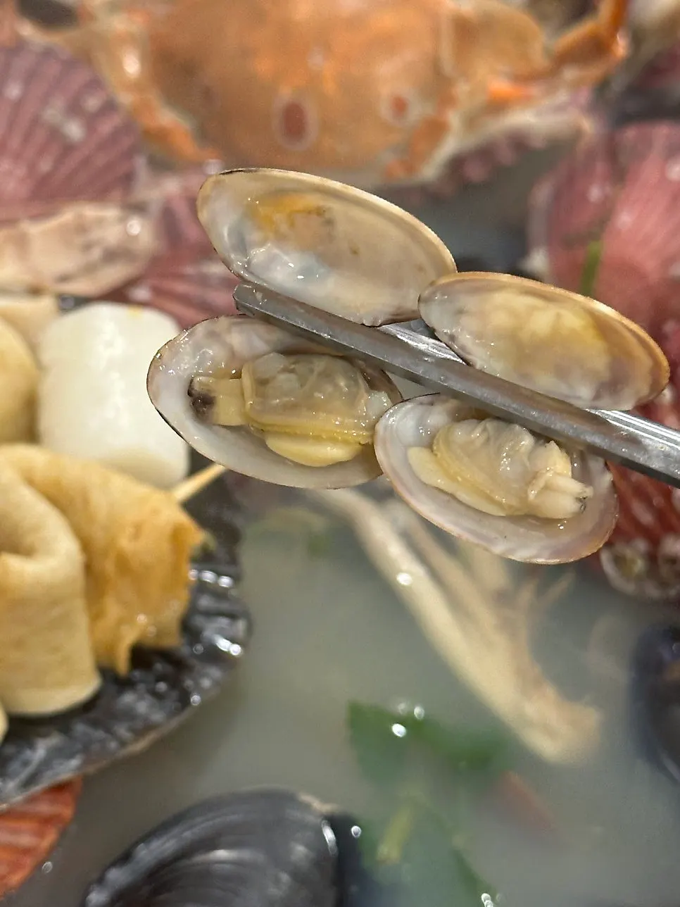 Blue crab and small clams sitting in the broth