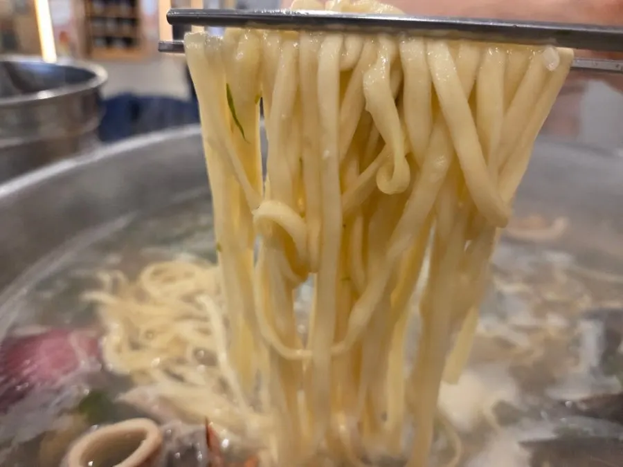 Kalguksu noodles cooking in the clam broth