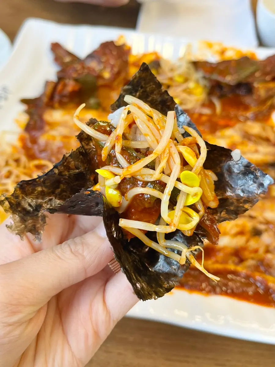 Gim topped with rice, seasoned bean sprouts, and chili for one bite
