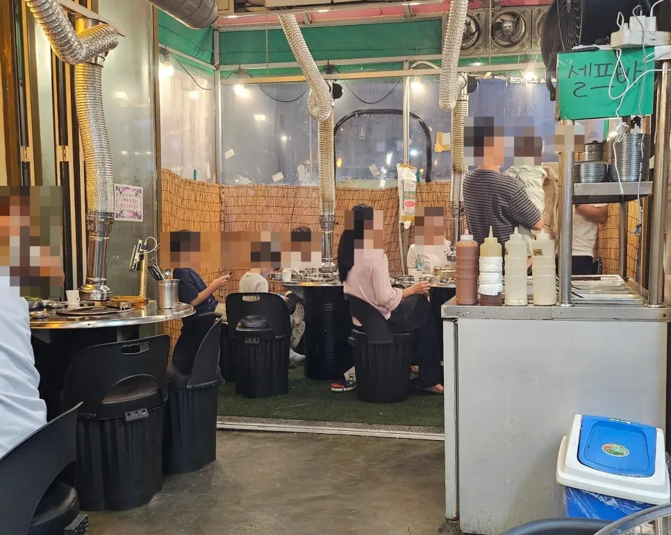 드럼통 테이블과 손글씨 메뉴판이 있는 매장 내부