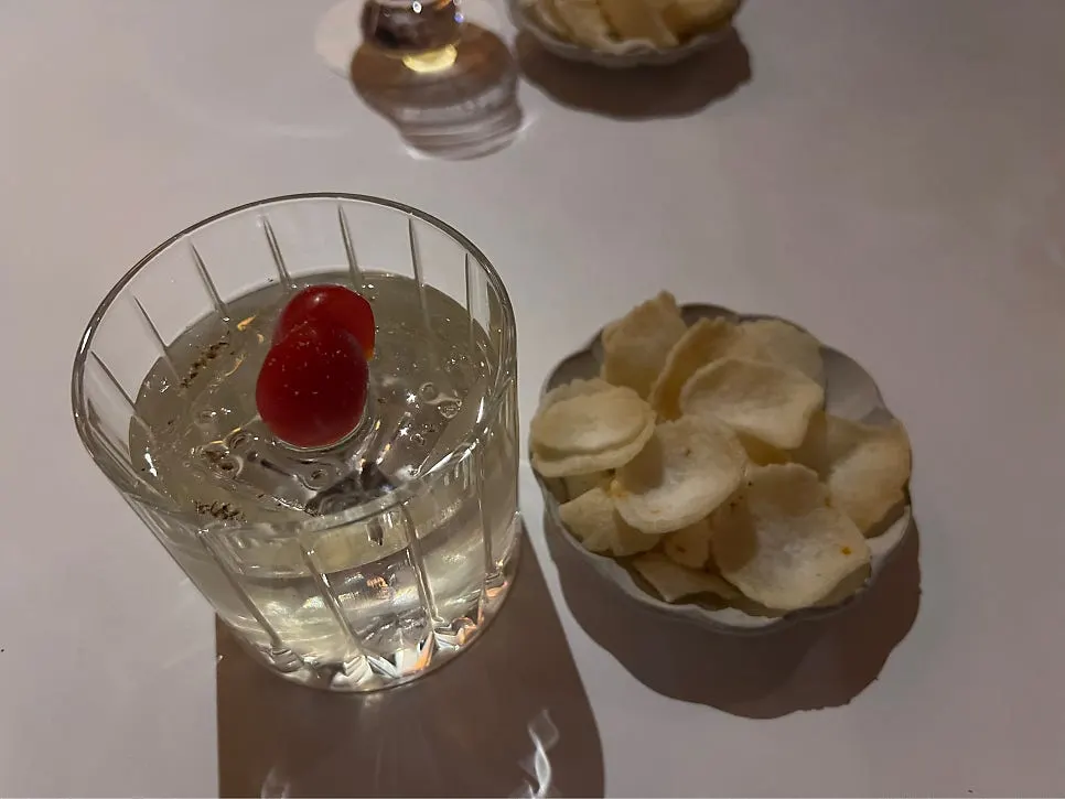 Basic snack served alongside a cocktail glass at Gak Seoul