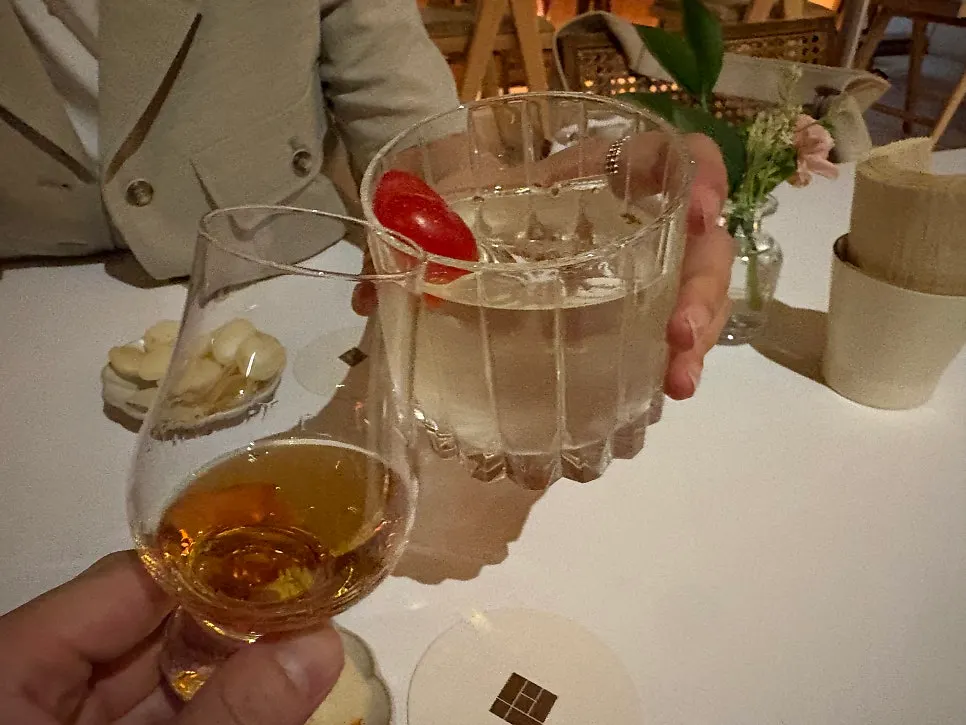 Cocktail and whiskey glasses clinking together in a toast at Gak Seoul
