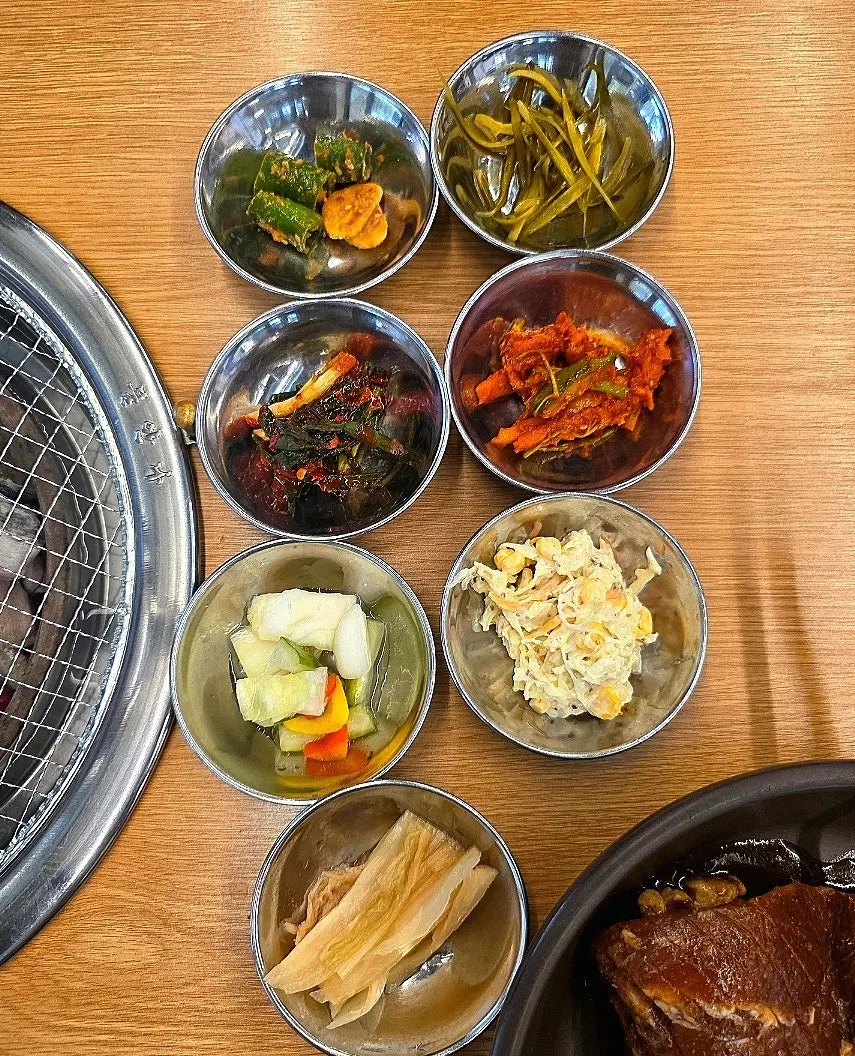 Assorted basic side dishes including lettuce wraps, pickles, and green onion kimchi
