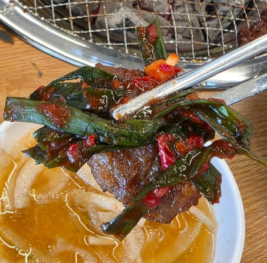 Grilled pork rib piece served alongside green onion kimchi