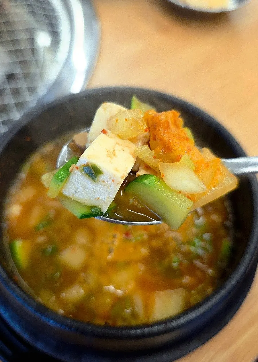 Spoon scooping up rich doenjang jjigae