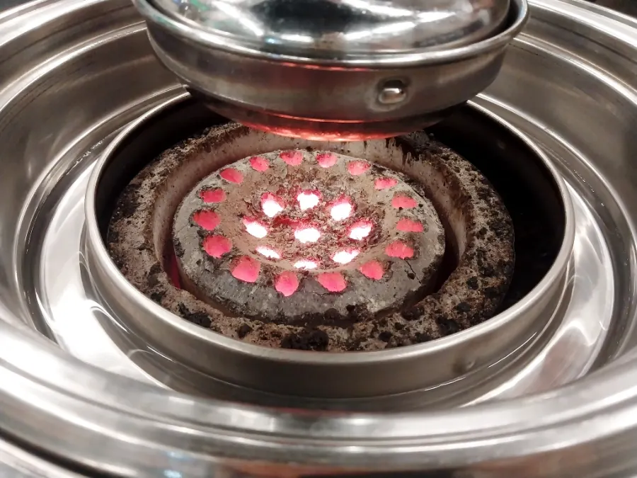 Charcoal fire and grill plate set up at the table