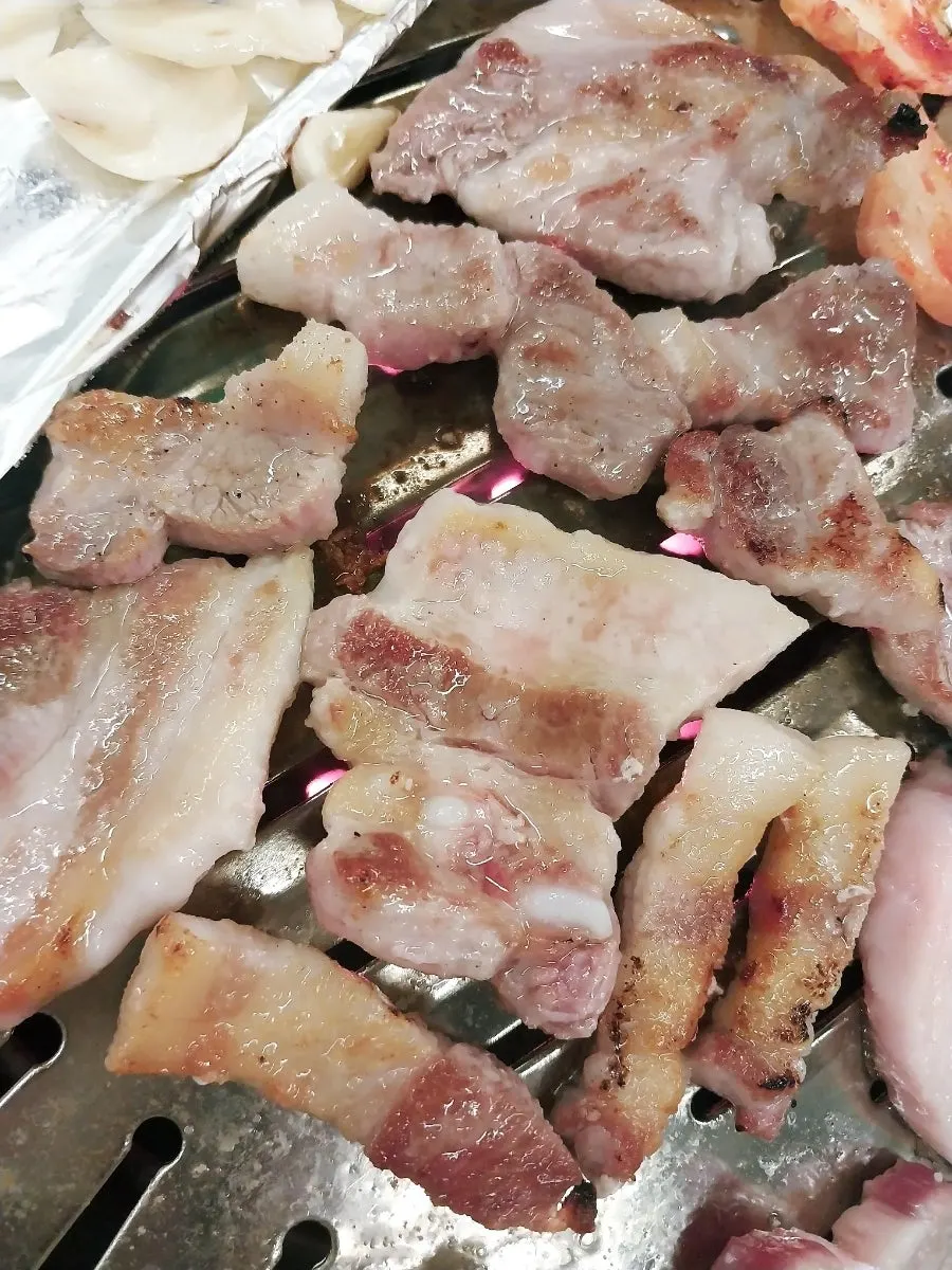 Pork belly grilling over charcoal fire