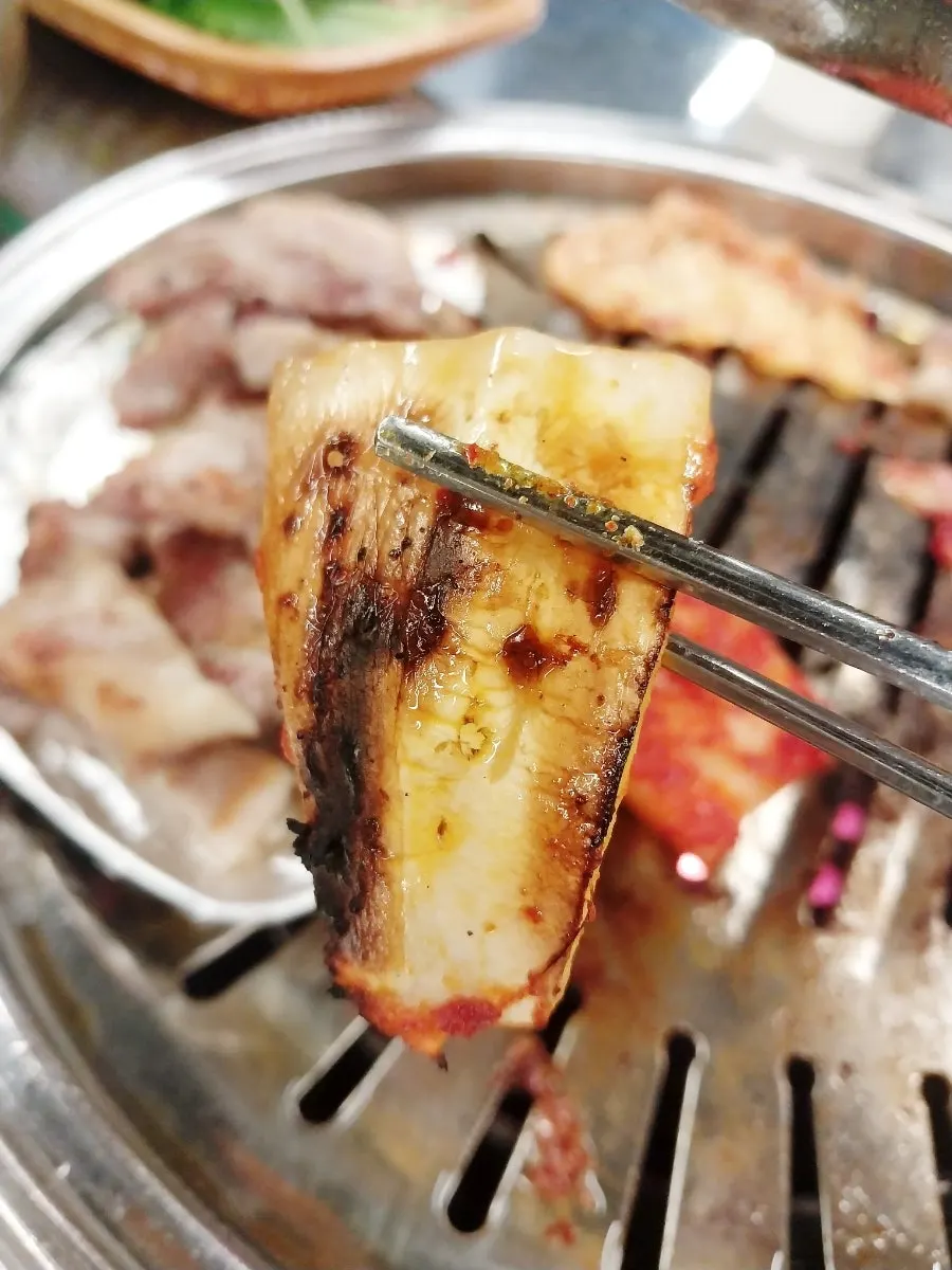 Kimchi placed on the grill plate alongside the meat