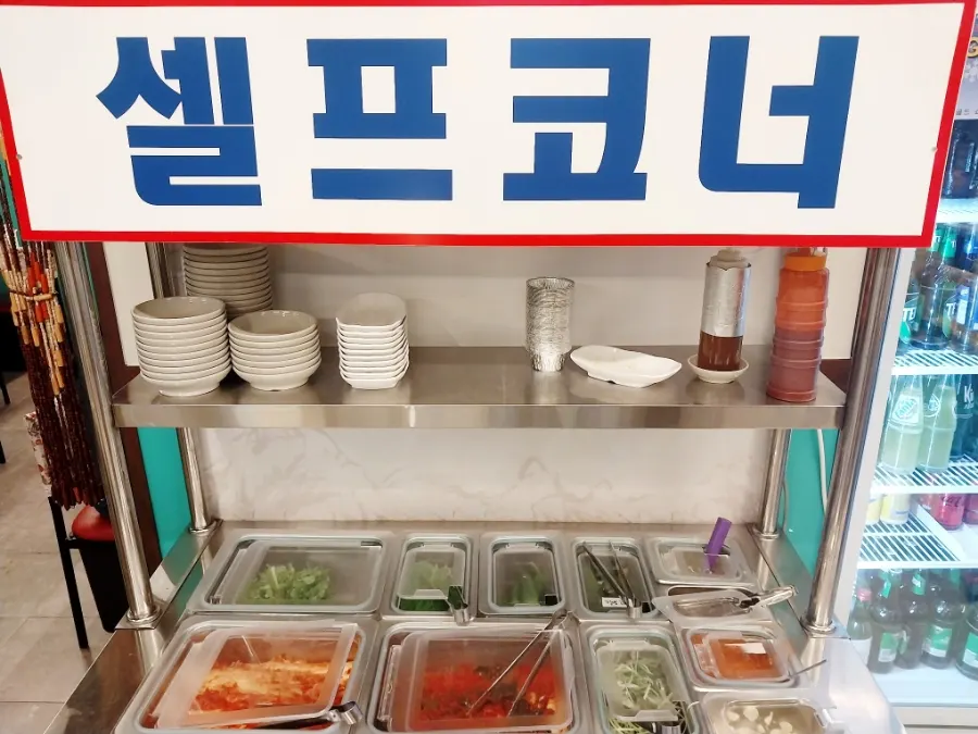 Self-serve side dish counter with pickled peppers and potato salad