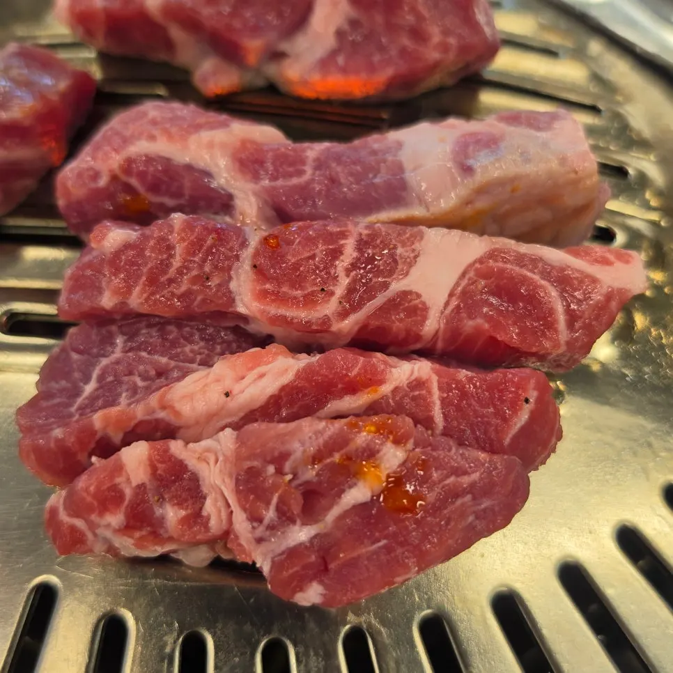 Pork neck beginning to cook on the grill