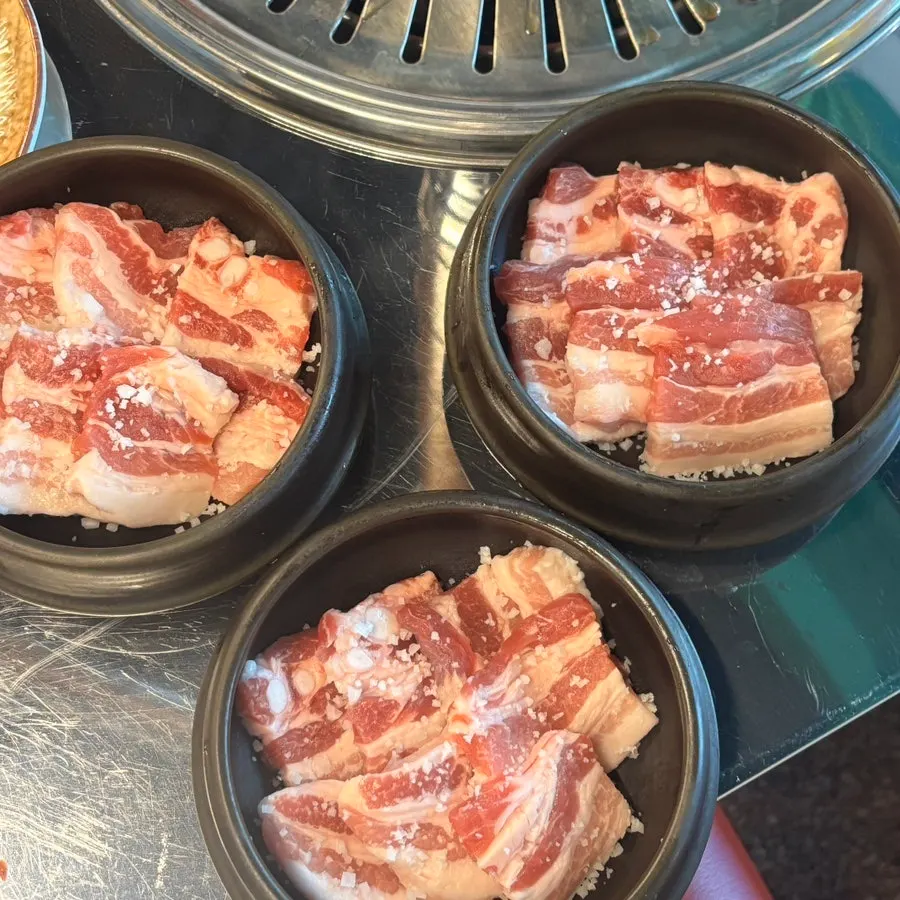 Table setup with 3 servings of charcoal coarse-salt pork belly, aged kimchi, and green onion kimchi