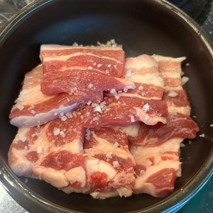Coarse-salt pork belly portioned into individual earthenware bowls