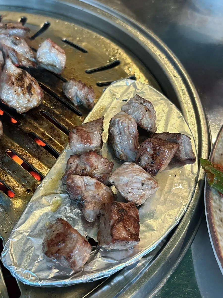 A piece of pork neck on a lettuce wrap with sides