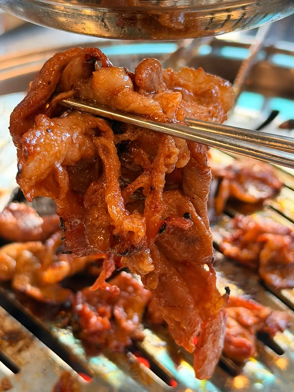 Charcoal bulgogi being flipped and cooked with tongs