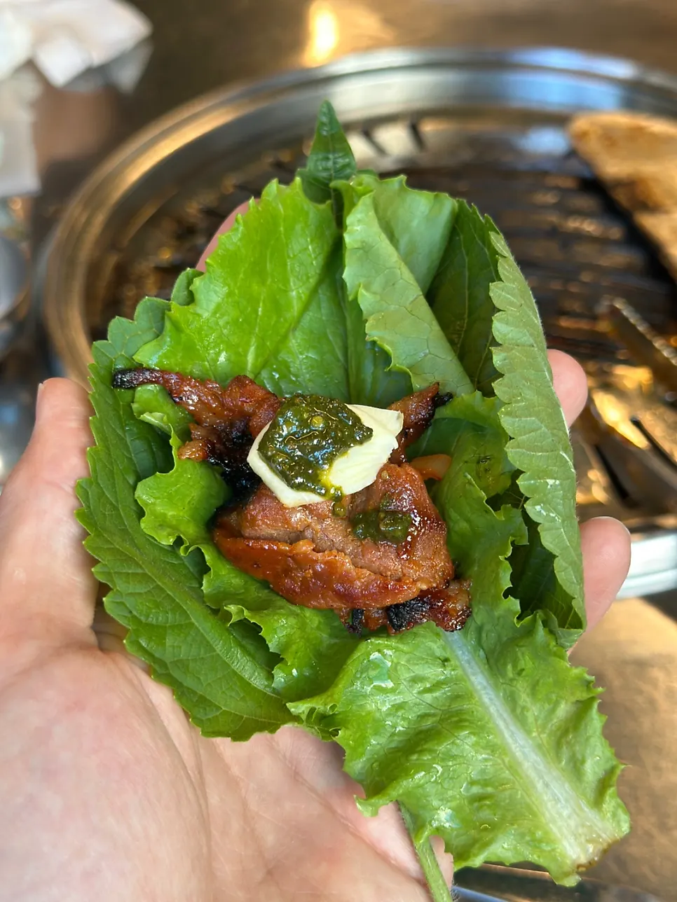 A wrap topped with kimchi and basil ssamjang