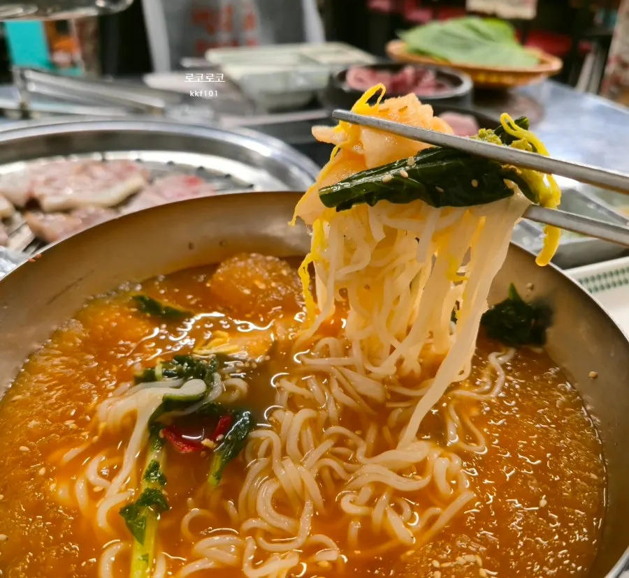 Kimchi noodle soup topped with crunchy yeolmu greens