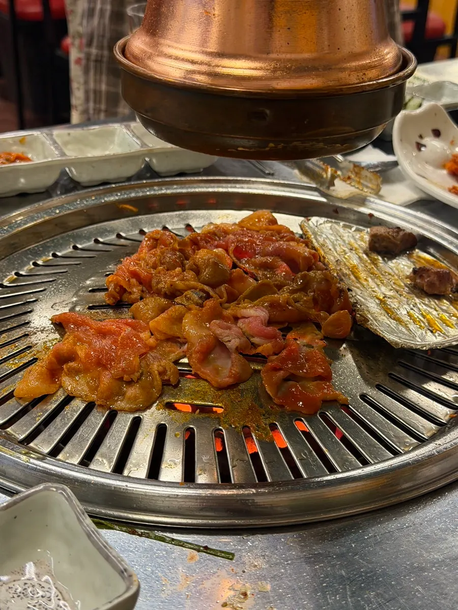 연탄 화로 위 고기와 반찬 상차림