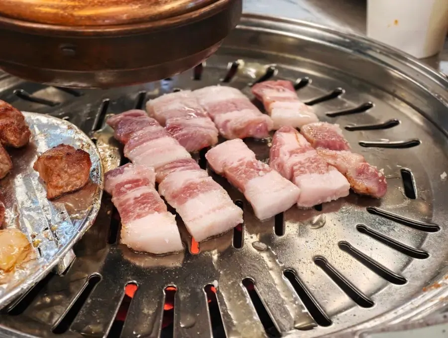 A shot of soju placed alongside the grilled meat
