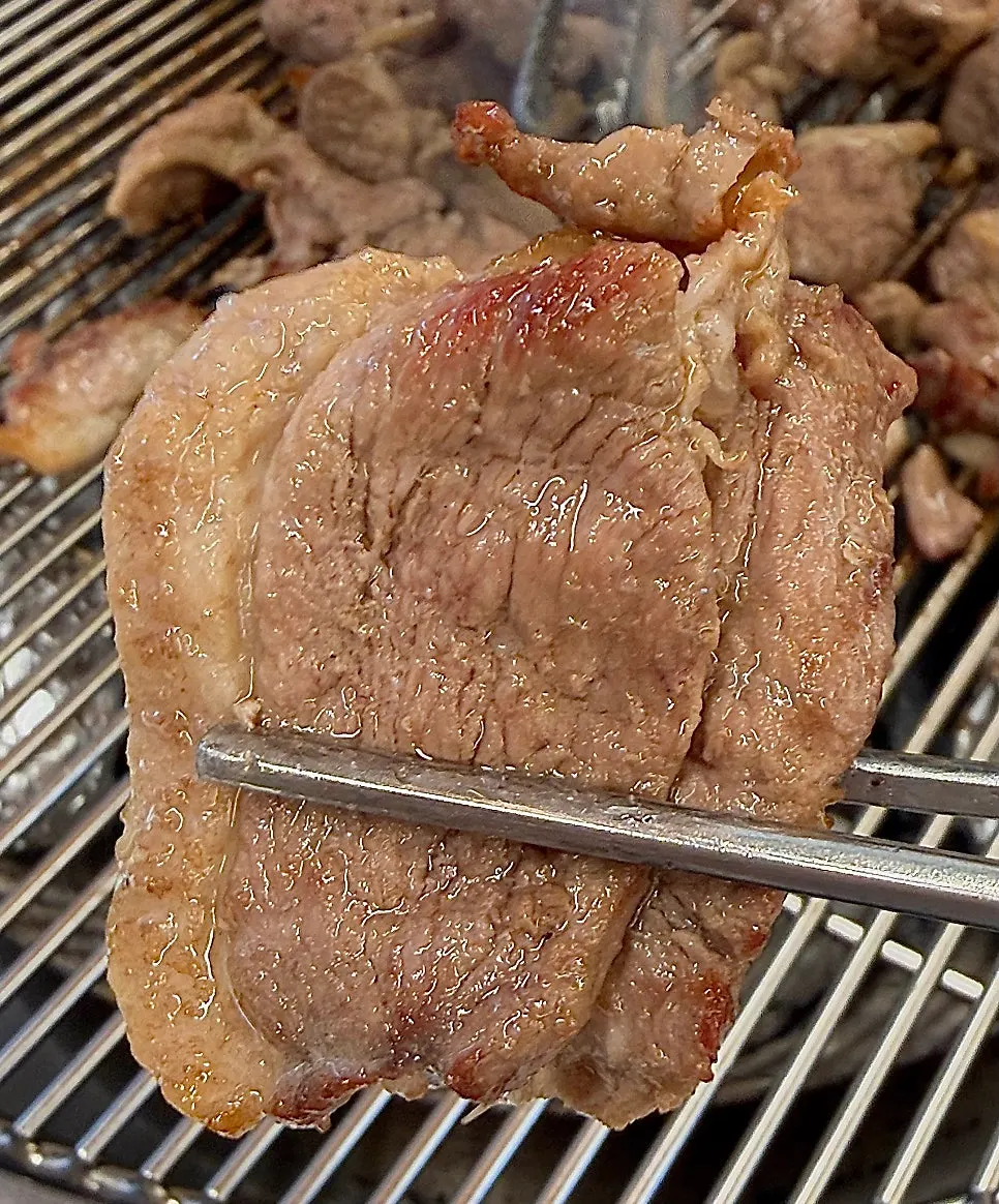 Raw duck grilling over charcoal