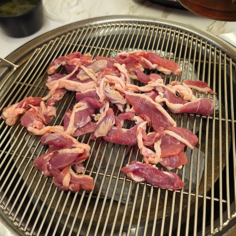 Raw duck meat and whole garlic on the grill grate
