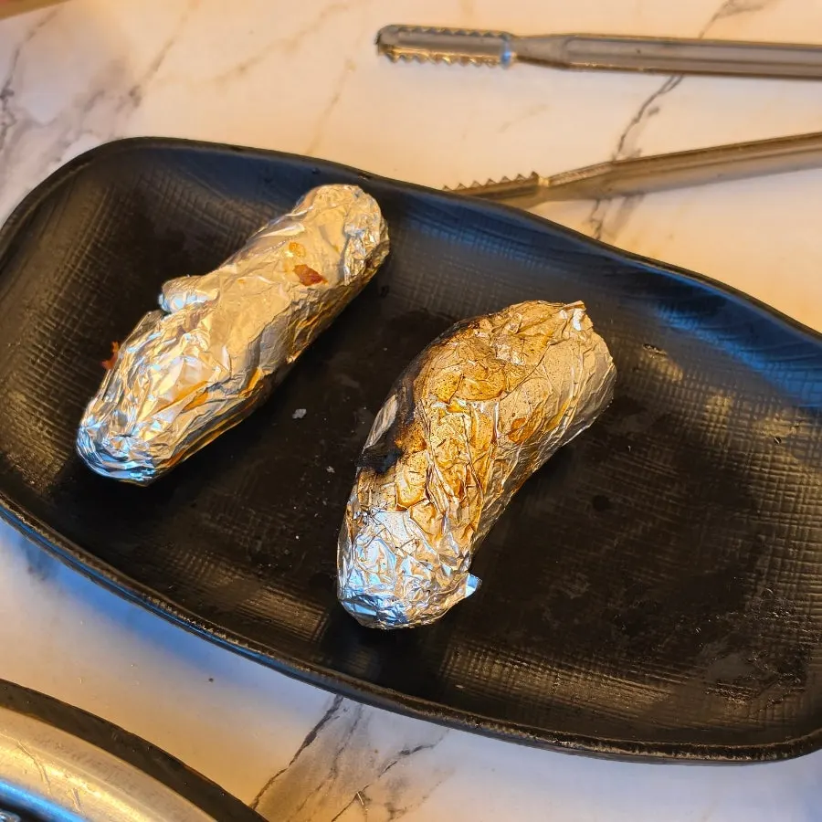 Foil-wrapped roasted sweet potato pulled from the charcoal grill