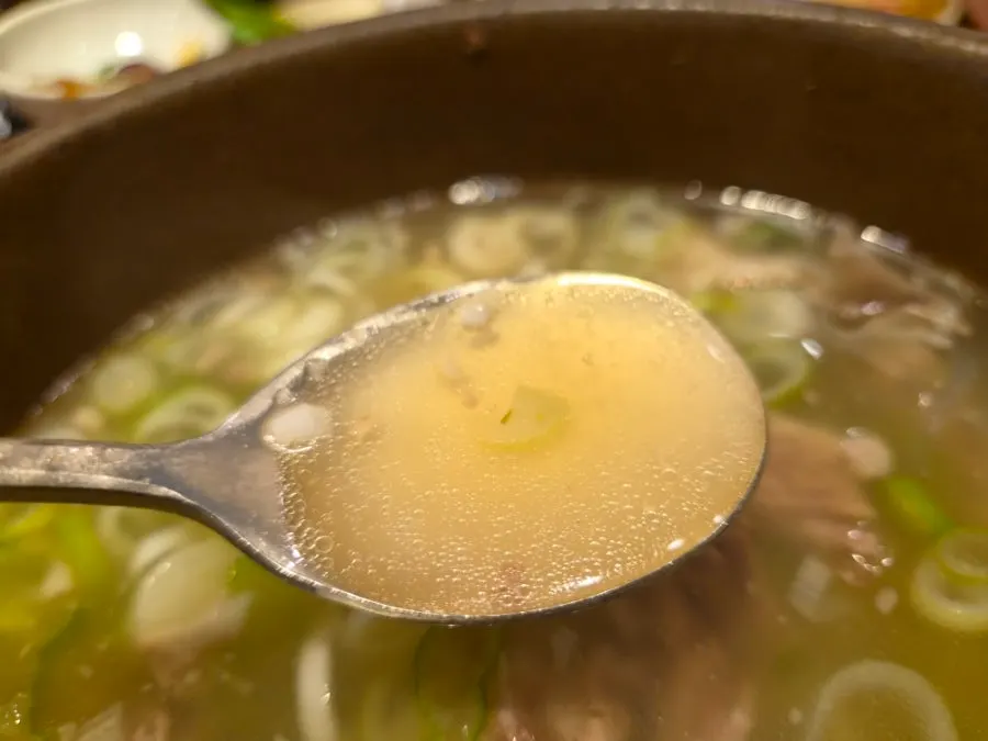 An opened stone pot of gang galbitang with steam rising