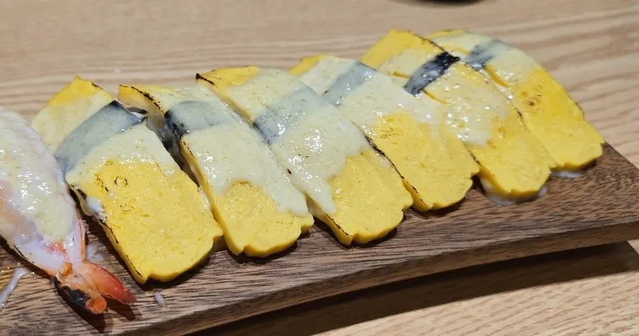 Flame-seared egg sushi with seaweed wrapped around the center