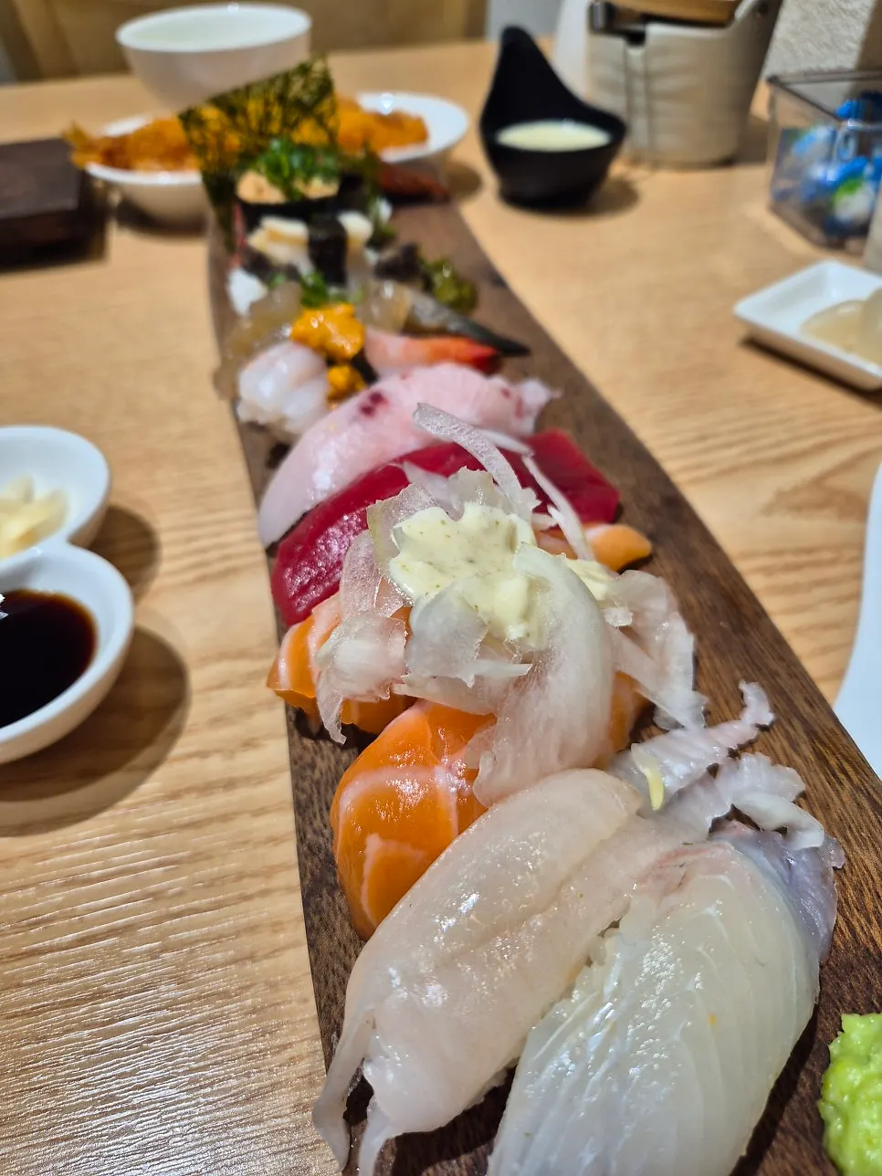 12-piece omakase sushi lined up in a row on a long wooden plate
