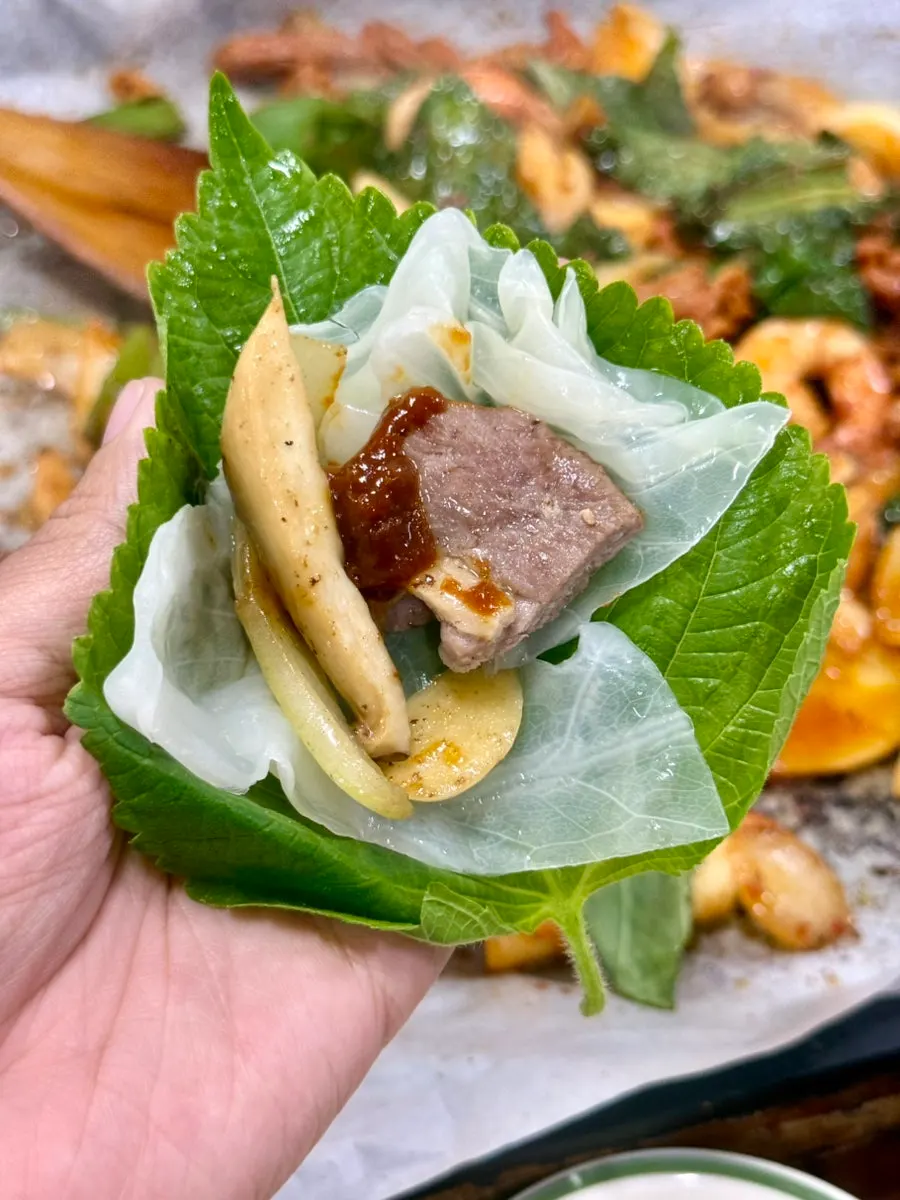 A piece of duck roast on a perilla leaf wrap
