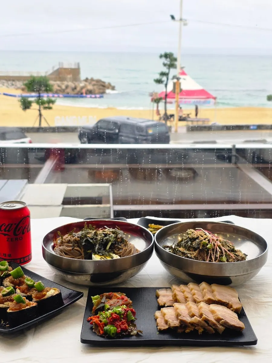 창가 테이블에 놓인 막국수와 바다 풍경