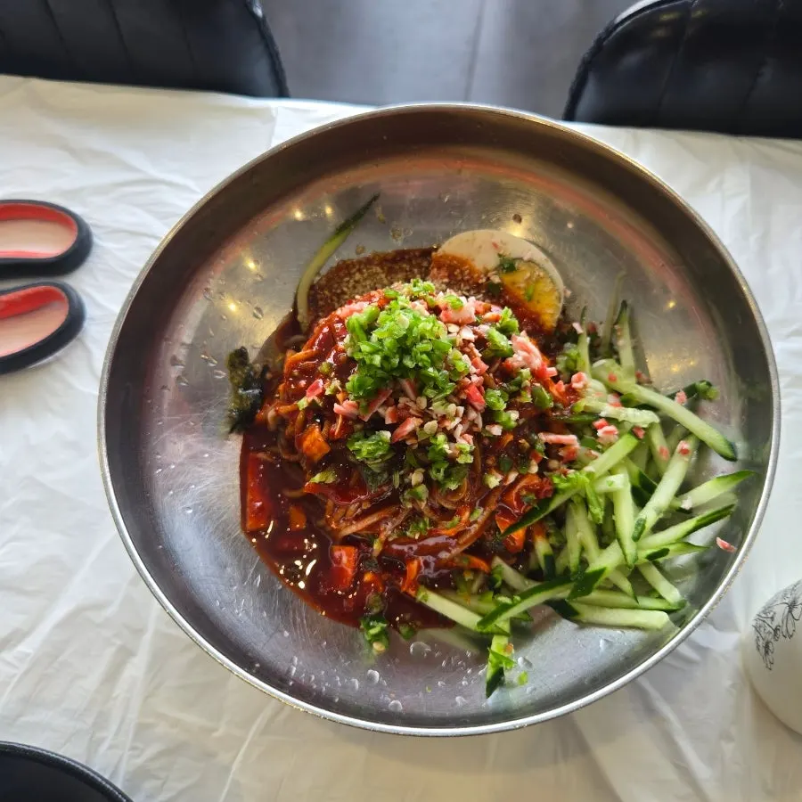 Bibim makguksu topped with cucumber and garnishes