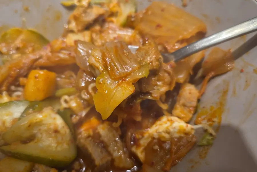 Inside the jjageuli showing meat, tofu, kimchi, zucchini, and potato