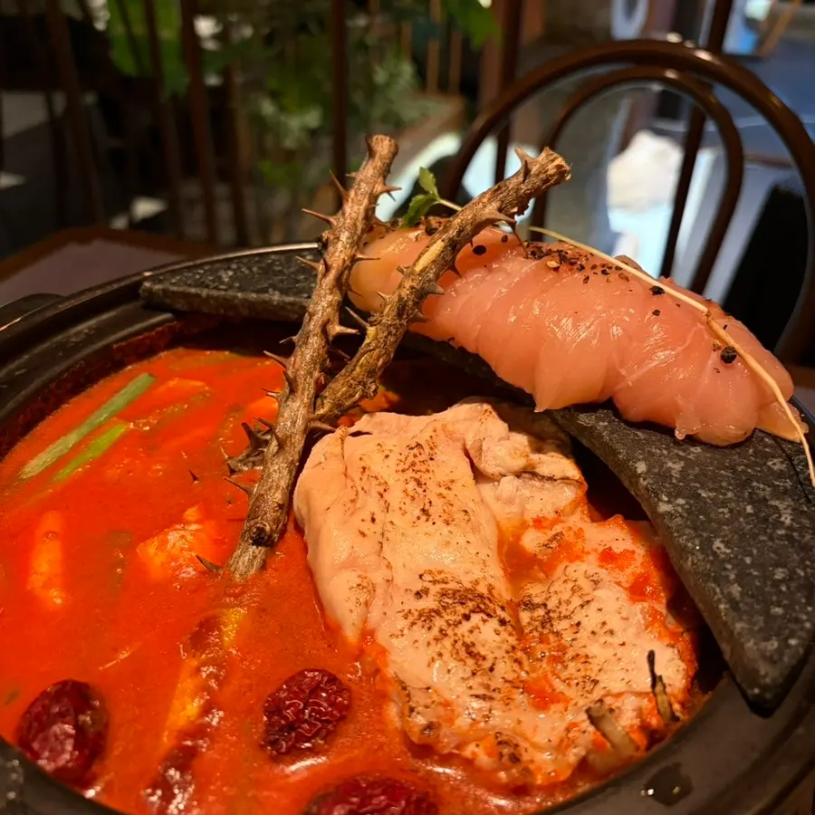 A ladle scooping up the spicy chicken hot pot broth