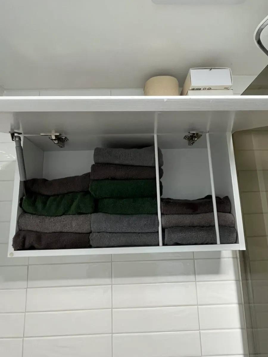 Upper cabinet in the bathroom stocked with towels