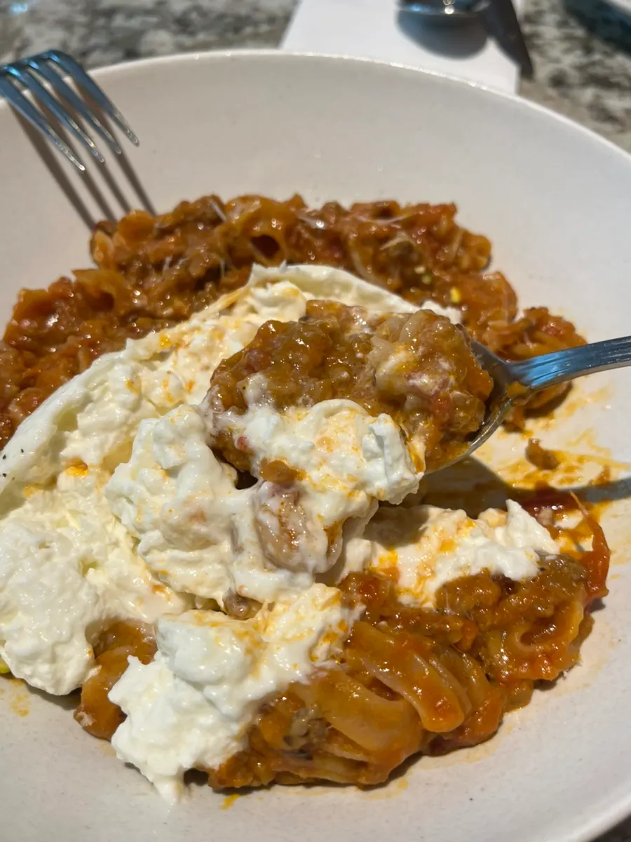 Mixing burrata cheese into Bolognese pasta