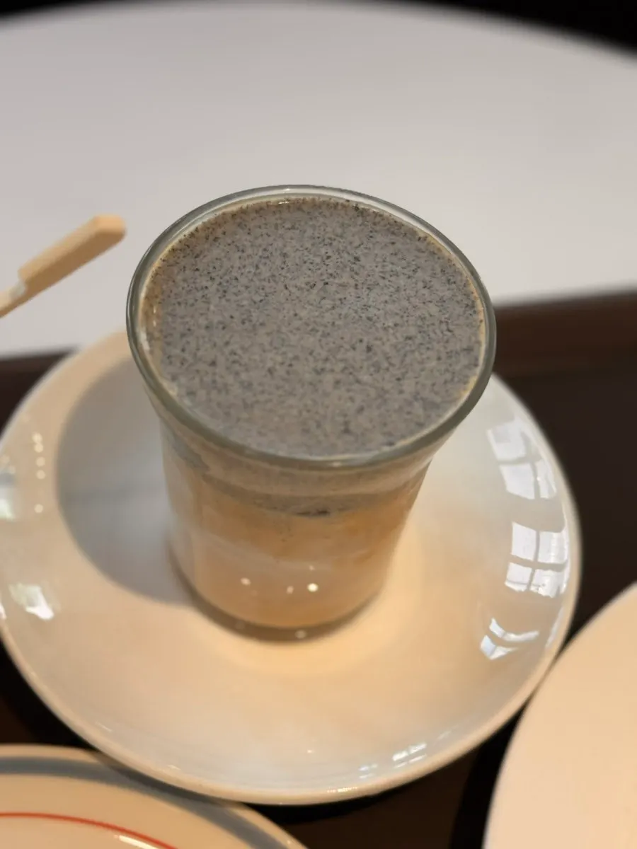 Nutty black sesame latte alongside dessert