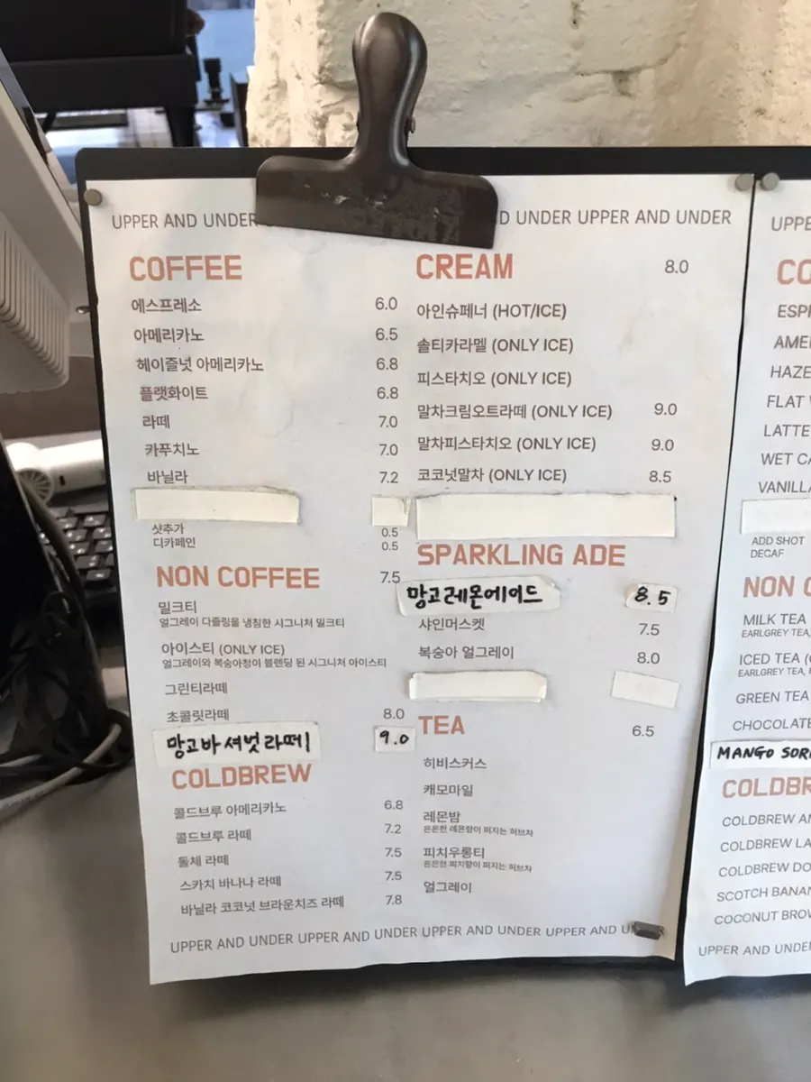 Upper and Under's drink menu board with various cream lattes