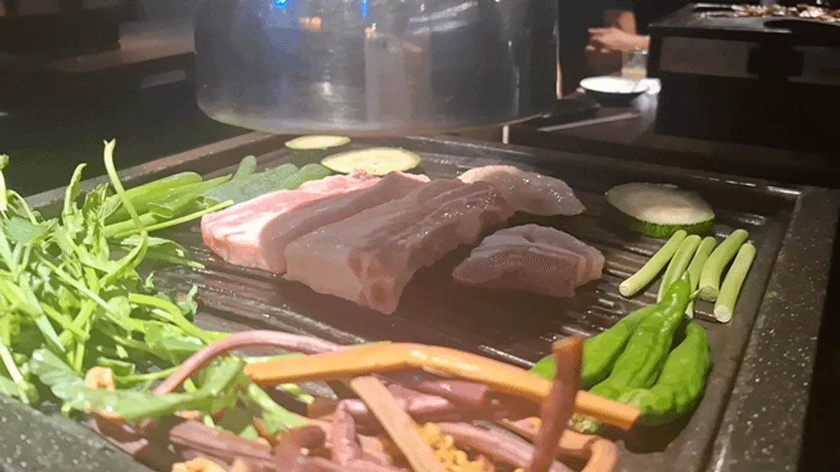 직원이 숯불에 갈비삼겹을 굽는 모습