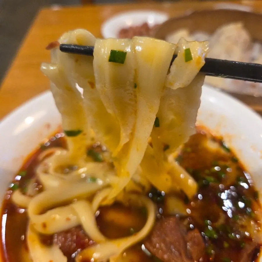 Thick, flat dosakmyeon noodles lifted with chopsticks